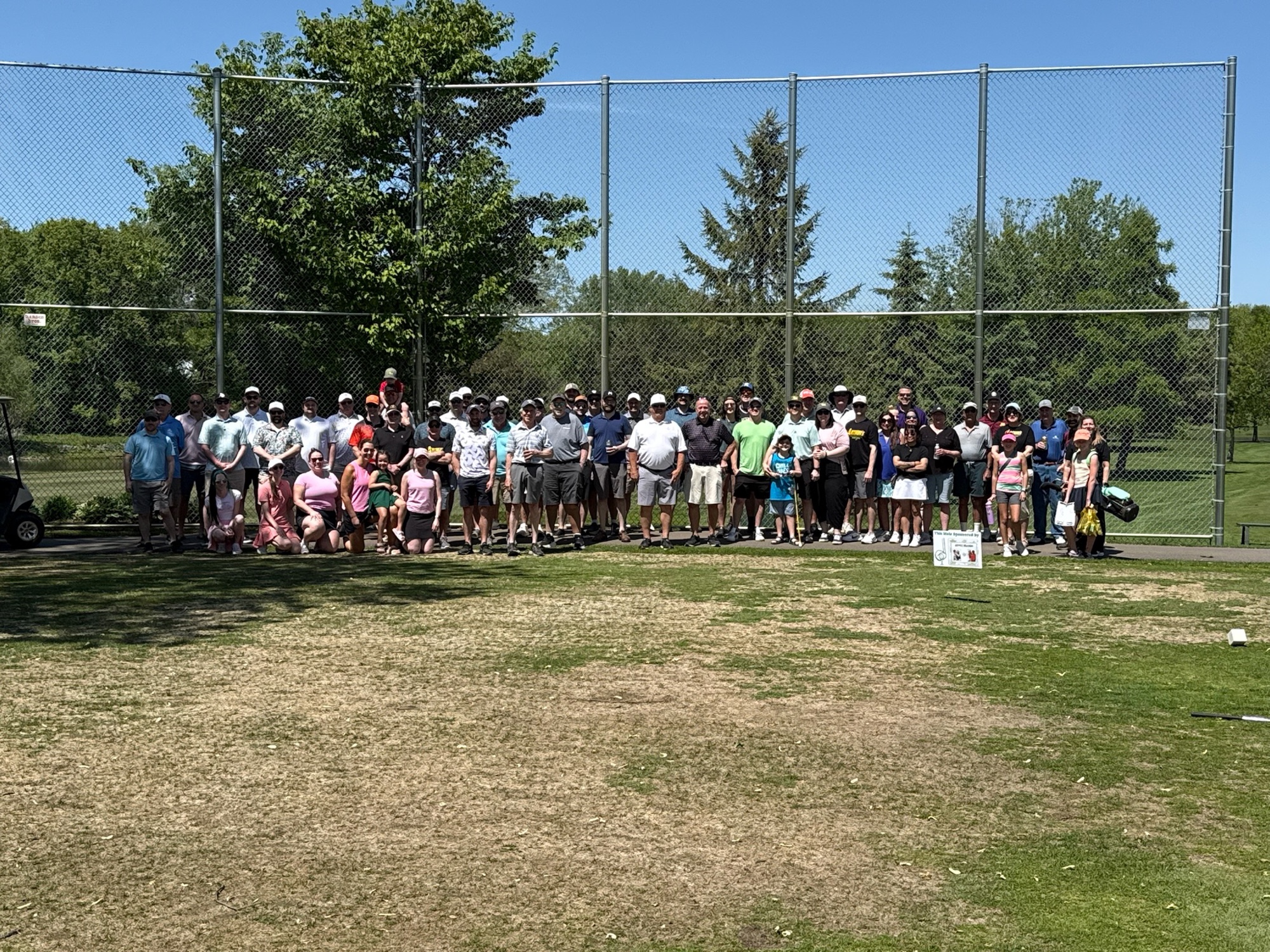 A large group of golfers, families, and volunteers gathered together at the Swing for Childhood Cancer golf tournament